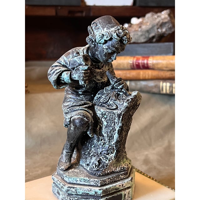 Vintage plaster figure of young Michelangelo carving a mask in dark bronze finish mounted on the 19th century white marble...