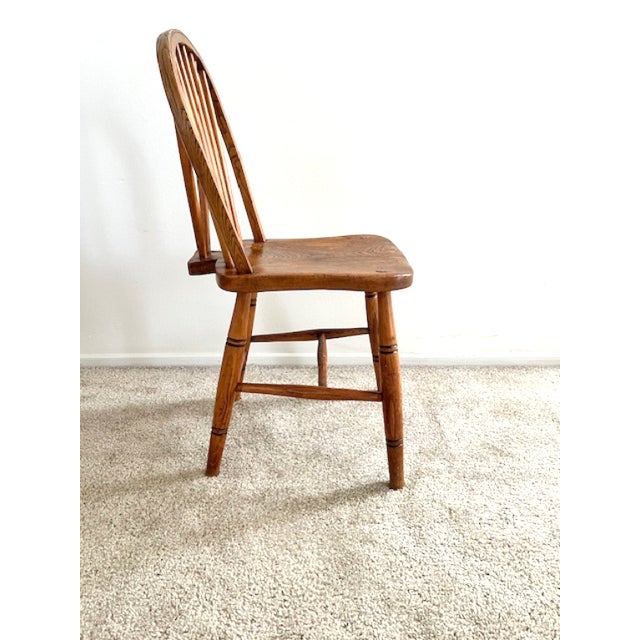 Rustic farmhouse bow-back side chair in solid hardwood with a warm, timeworn patina. A gently arched back, slim spindles...