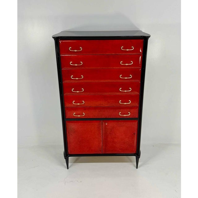 Elegant chest of drawers produced in Italy in the 1950s. The drawers are veneered in red parchment, framed by a black...