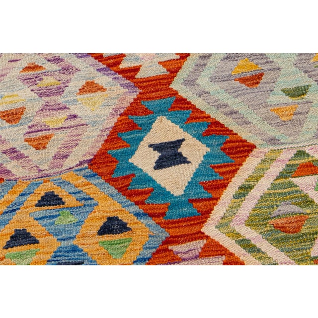 A contemporary kilim rug showcases an exuberant and detailed geometric motif throughout, employing a variety of...