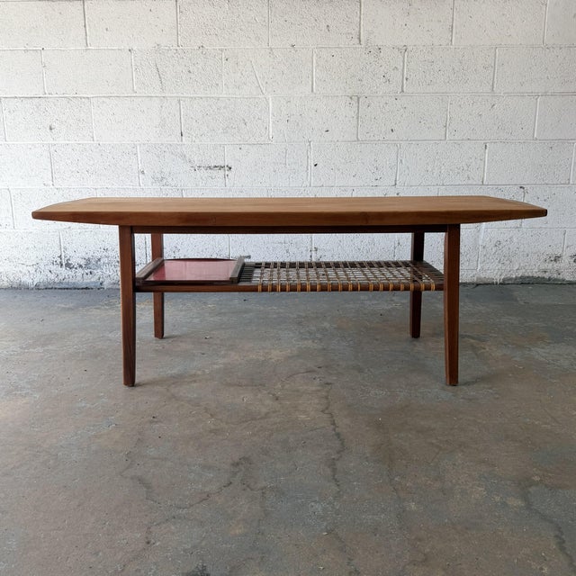 A Danish modern teak coffee table dating to the 1960s, with a long rectangular top, softly shaped edges, and a lower...