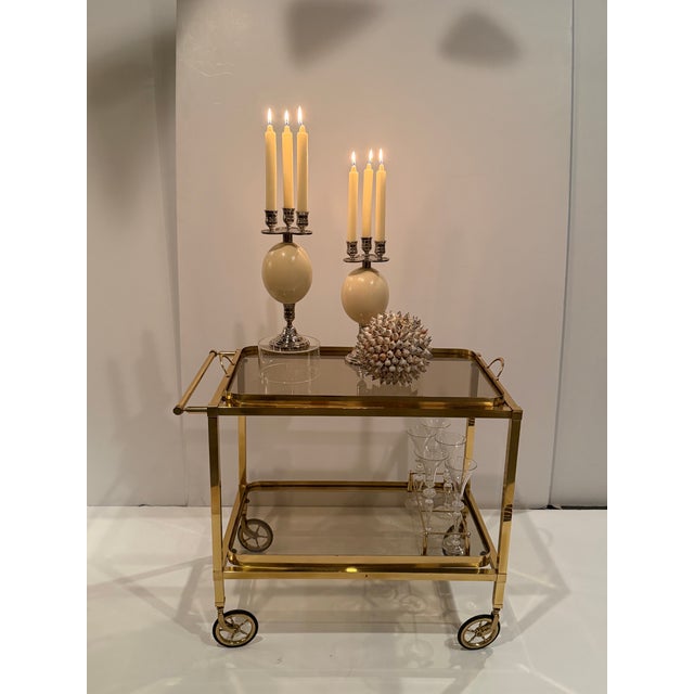 Brass and tinted glass mid-century modern bar cart having re-moveable top tray for serving with handles and elegant brass...