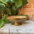 Vintage hammered brass pedestal bowl featuring elegant serpentine handles, rope edging, and a classic fluted pedestal. The...