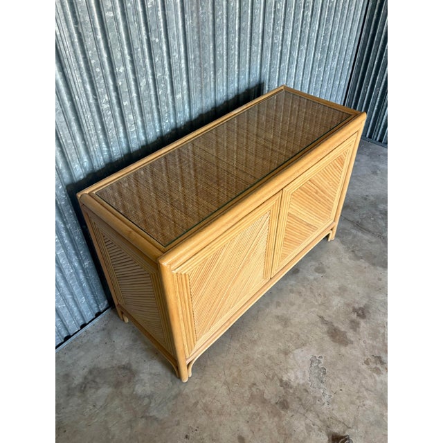 A beautifully crafted vintage coastal credenza showcasing refined split reed detailing across both door fronts, framed by...