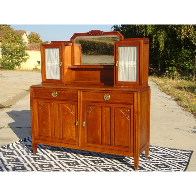 A two-door, two-drawer sideboard surmounted by two small cabinets framing a mirror. The glass-fronted cabinets feature...