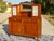 A two-door, two-drawer sideboard surmounted by two small cabinets framing a mirror. The glass-fronted cabinets feature...