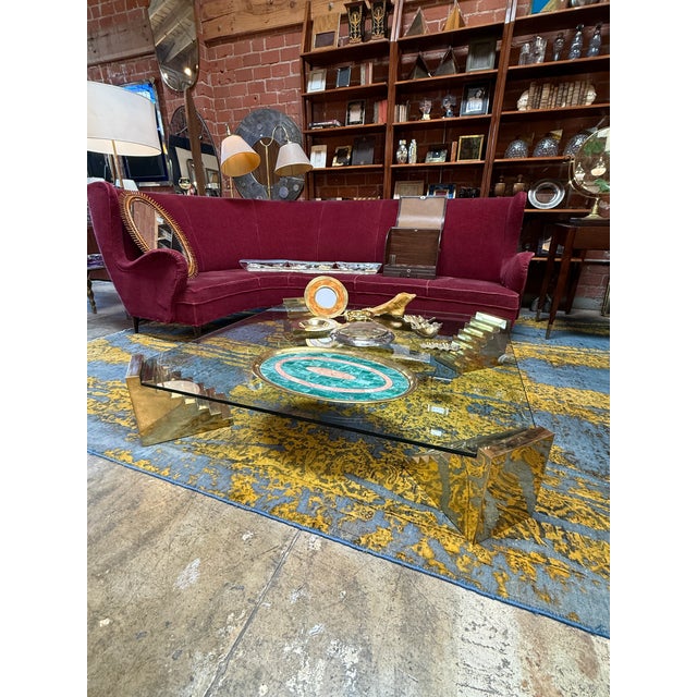 Exceptional vintage sculptural coffee table featuring a thick square glass top supported by four dramatic stepped brass...