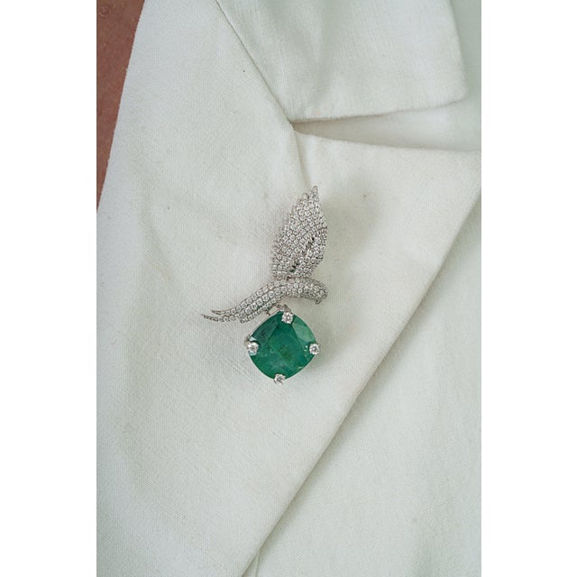 This elegant bird brooch features a vibrant 6.59 carat green emerald set in 14K white gold. The emerald measuring...