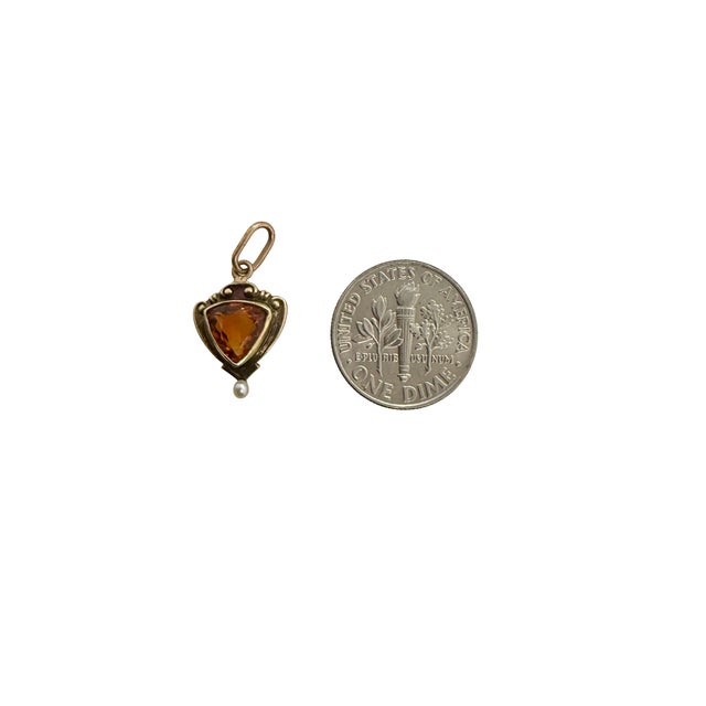 A fine Art Nouveau period 14K yellow gold charm with a triangular shaped bezel set faceted sapphire in the center and a...