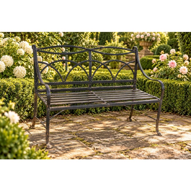 A striking vintage Regency-style garden bench crafted from painted iron with elegant reeded strapwork. The open back...