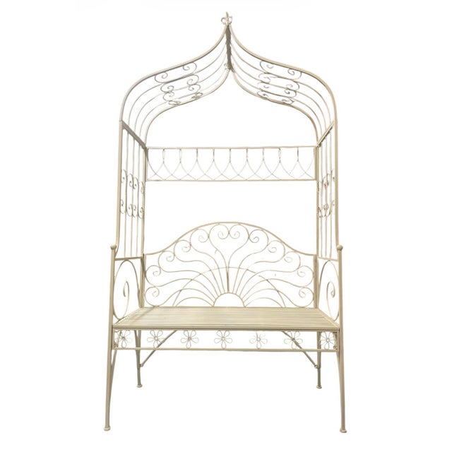 A wrought iron canopy bench. Finished in a crisp, clean white, this piece serves as both a functional seat and a...