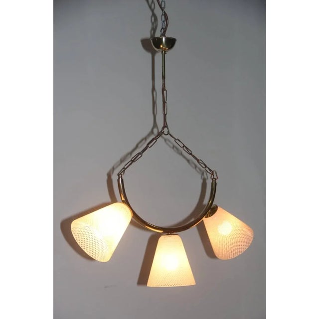 This 1950s ceiling lamp is comprised of brass, Murano glass and reticello. Up to 250V (Europe/UK Standard).The wiring of...