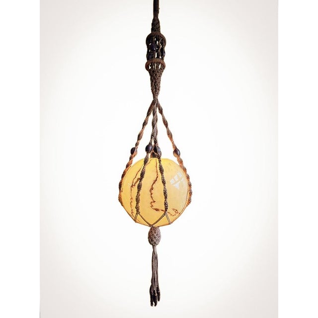 Rare handcrafted pendant lamp, made from braided brown rope with wooden beads, and a globe of beige marble glass. with a...