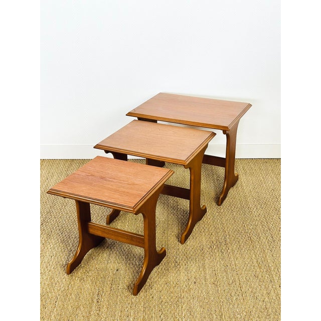 Elegant trio of vintage nesting tables with a design typical of the 1960s. made of teak veneer, they feature a beautiful...