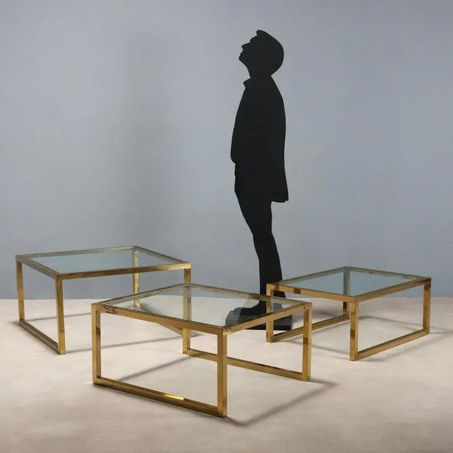 Three nesting tables with brass frames and square tops of varying sizes. In good overall condition with some signs of...