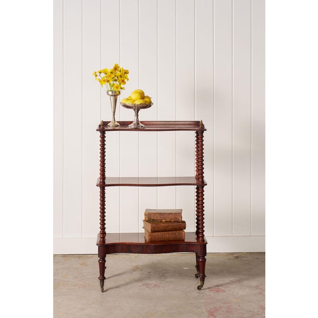 Elegant Victorian mahogany three-tier whatnot featuring turned bobbin legs, rolling casters, and warm aged patina