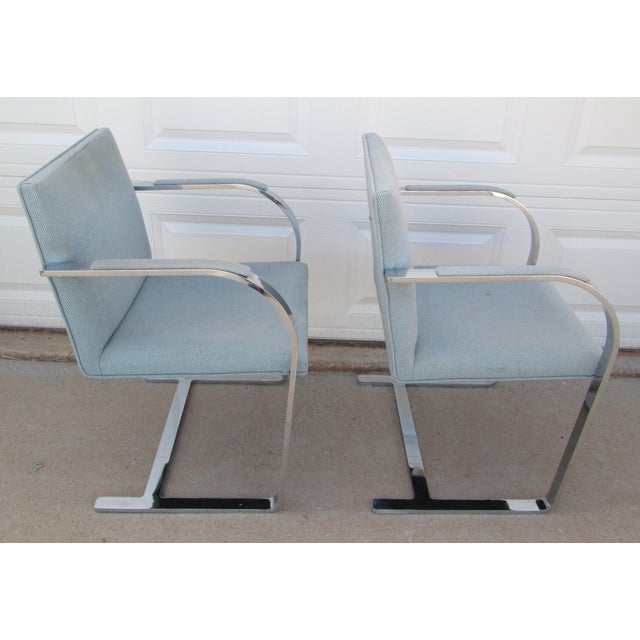 2 flat arm Brno chairs designed by Ludwig Mies van der Rohe made by Gordon International. Both have light blue fabric. One...