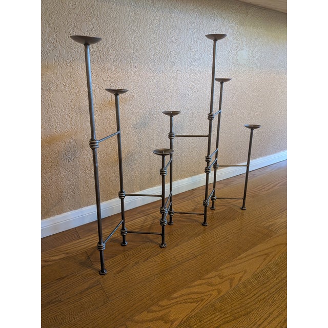 A striking extendable wrought iron candelabra featuring an architectural, sculptural silhouette with varying heights and...