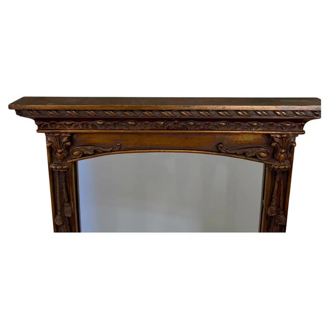 A striking Regency‑style carved wood wall mirror, this tall pier‑form design features beautifully sculpted draped tassel...