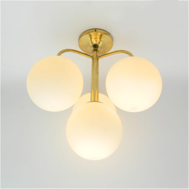 Ceiling lamp made of brass with four white glass balls designed by e. R. Nele for the company temde switzerland. This is a...