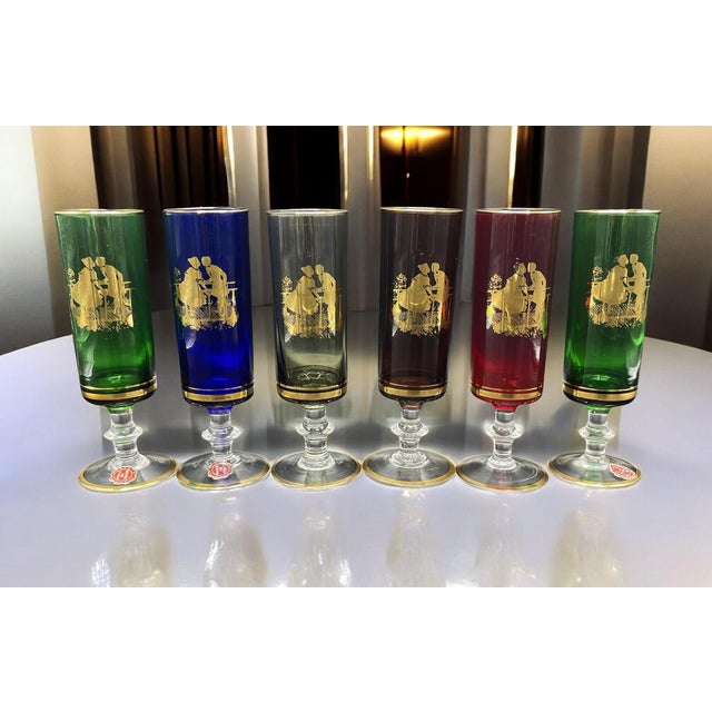 The set includes six glasses in various shades with gold decorations depicting romantic scenes. Their precise origin is...