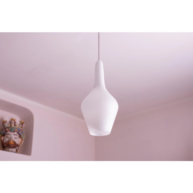 Stilnovo design opaline glass pendant made in the 1970s. It connects to the ceiling with a brass element; the wire cover...