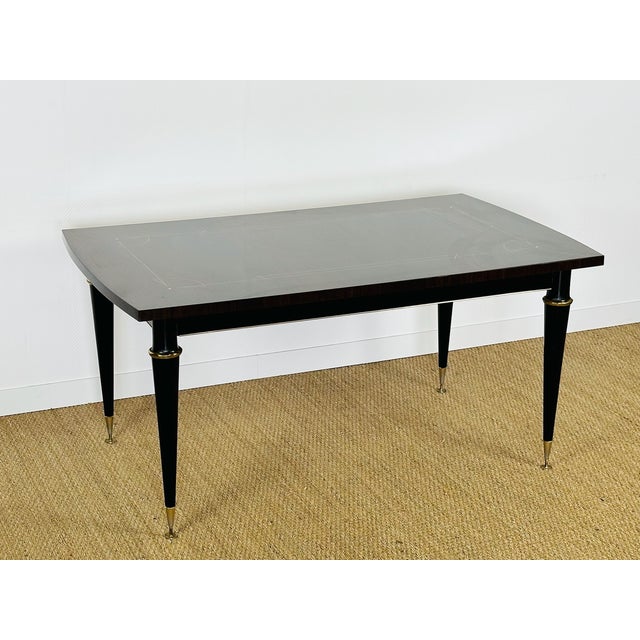 An elegant 1950s modernist dining table, crafted from dark precious wood veneer, specifically macassar ebony, offering...