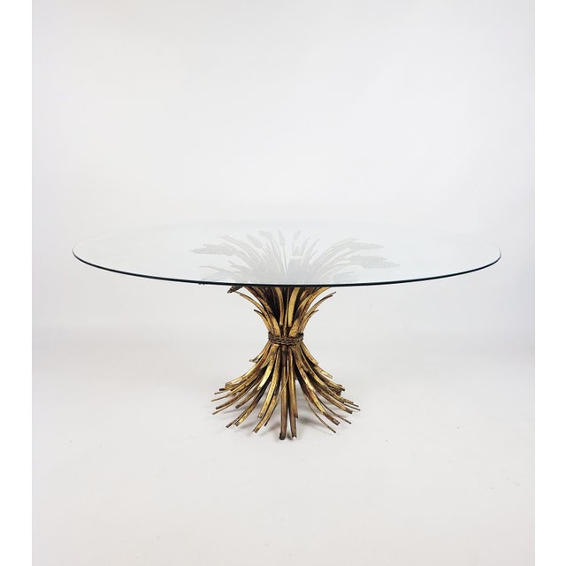 An elegant 1960s Hollywood Regency table with a striking gold spike base and a round glass top. This iconic design from...
