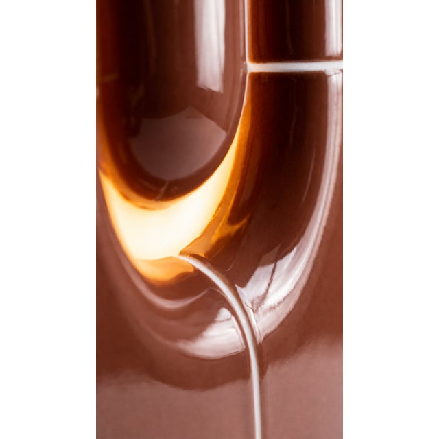 The vertical one. Where the rest of the collection sits low and grounded, this table lamp rises in a slim column of curved...