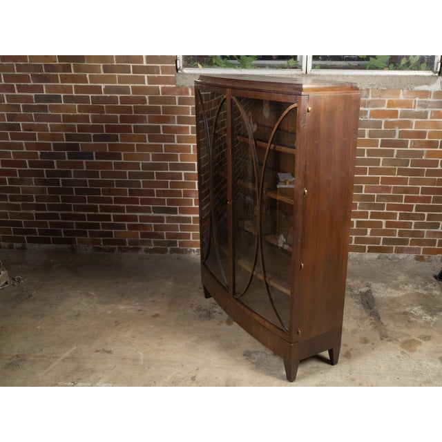 A wooden bow front vitrine cabinet attributed to Barbara Barry for Henredon from the late 20th century with oval motifs,...