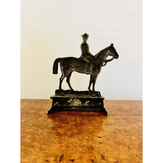 Quality antique brass ornate 'Dr Jim' doorstop having a modelled figure on horseback above a crossed spear and scroll...