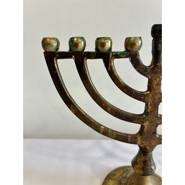 A vintage brass Hanukkah menorah featuring the traditional nine-light design, including a raised central shamash candle...