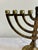 A vintage brass Hanukkah menorah featuring the traditional nine-light design, including a raised central shamash candle...