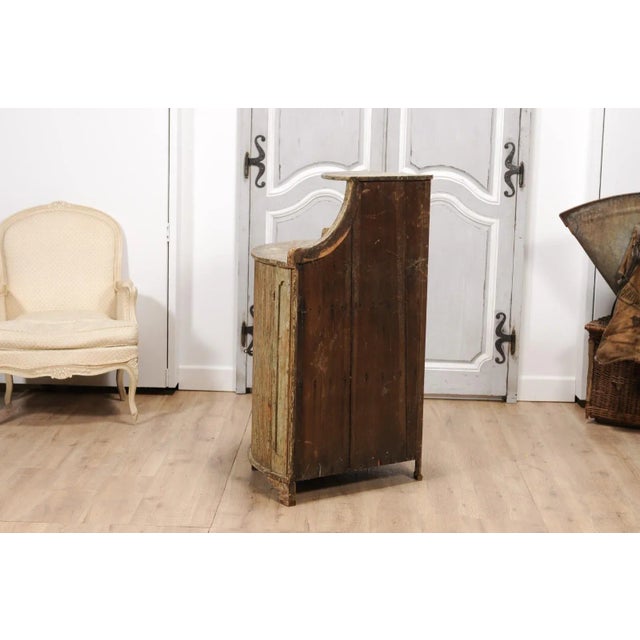 A Swedish Gustavian period painted corner buffet from the 18th century with open shelf at the top, bow front, carved...