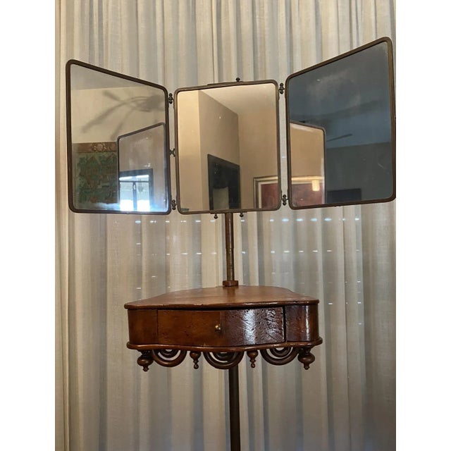 Early 20th-century barber's triptych mirror on an adjustable brass pedestal, equipped with a shelf where shaving...