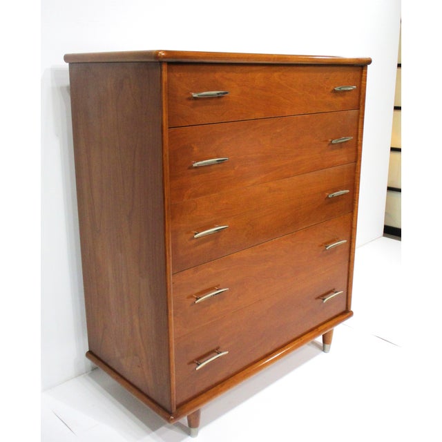 A very well crafted five drawer wood dresser with sculptural curved polished metal pulls having plenty of storage with the...