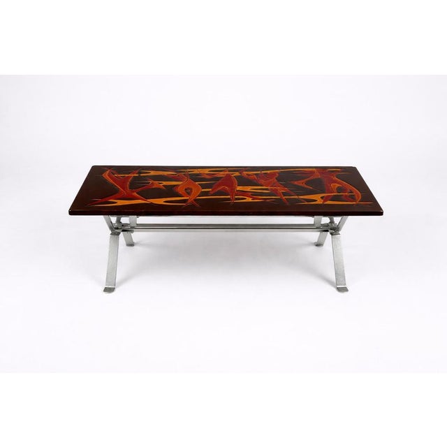 A striking and highly individual mid century modern coffee table, featuring a bold hand-painted flame motif set against a...