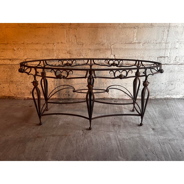 Oval table in the style of Gilbert Poillerat in lacquered, oxidized and gilded metal. It rests on six openwork spindle...