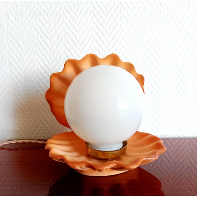 Coral-colored ceramic shell-shaped lamp with a white opaline glass globe replacing the pearl. Clean and functional wiring:...