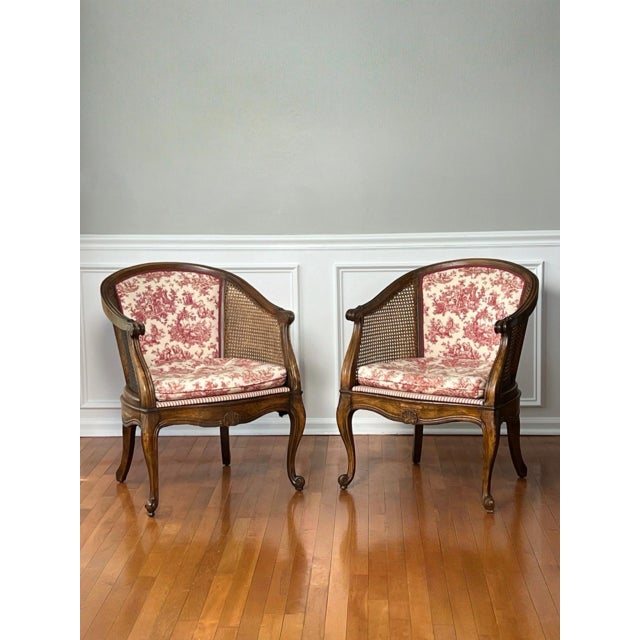 Pair of Louis XV style walnut and cane barrel back Bergere chairs in red and white toile, mid to late 20th century. The...