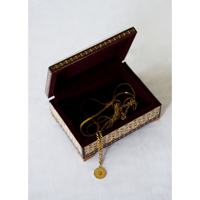 A wooden jewelry and keepsake box featuring a hand-painted miniature polo scene, framed by geometric marquetry borders....