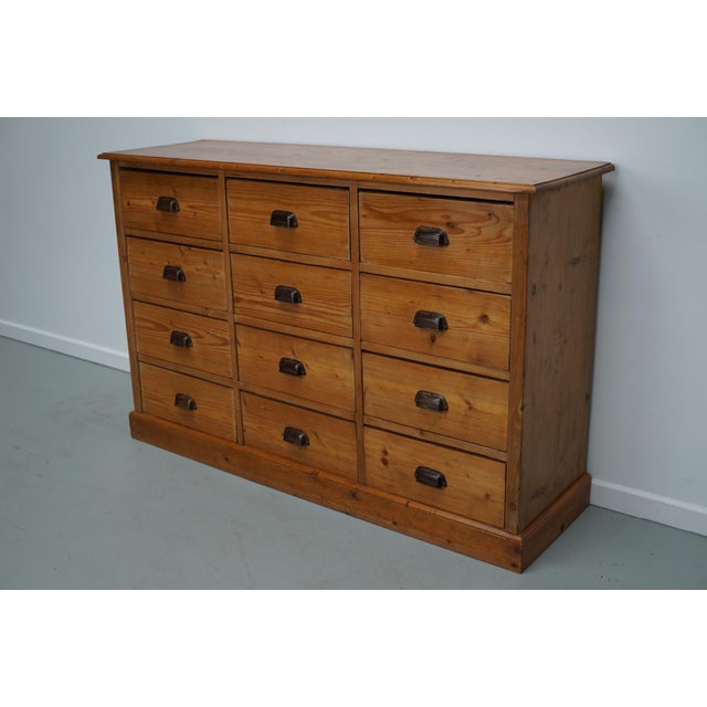 This apothecary bank of drawers was designed and made circa 1930. It was made from pine and it features 12 drawers with...