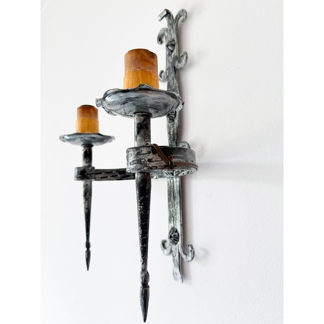 A wrought iron double wall sconce in arts & crafts style, most likely mid-20th century, with hand-forged decorative...