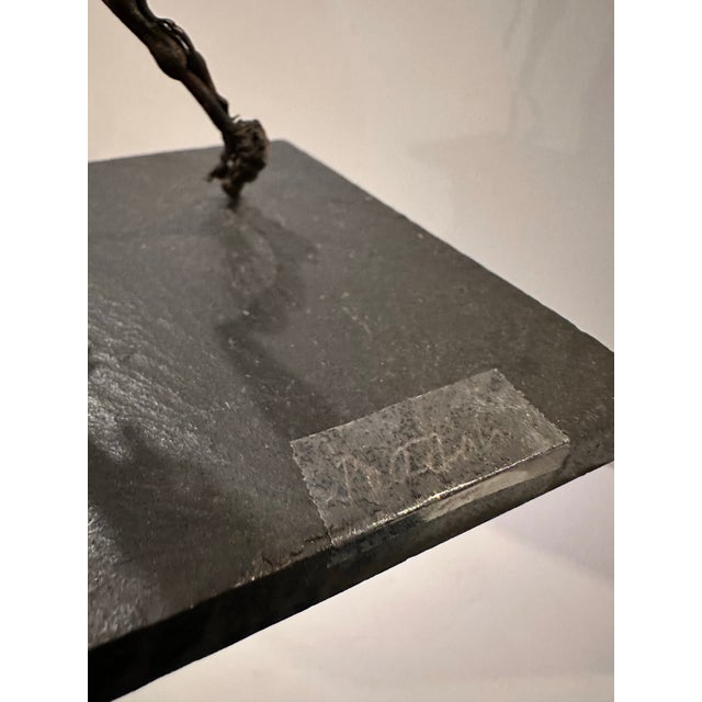 A brutalist mixed-metal sculpture depicting two elongated figures rendered in twisted wire and chain-link construction,...