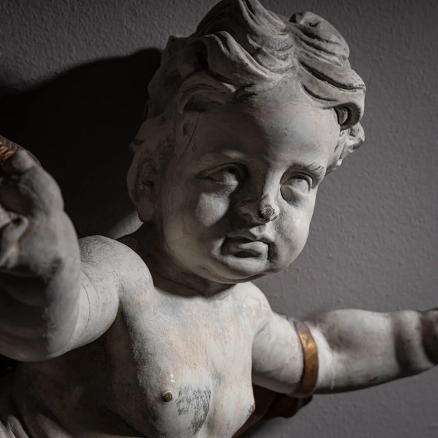 Expressive Baroque angel figure with an expansive gesture and wavy hair. The wings, arm band, and loincloth are gold-...