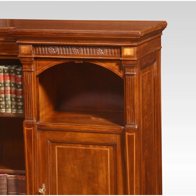 Mahogany inlaid corner bookcase. The well-figured large rectangular lipped top above carved freeze, to the adjustable...