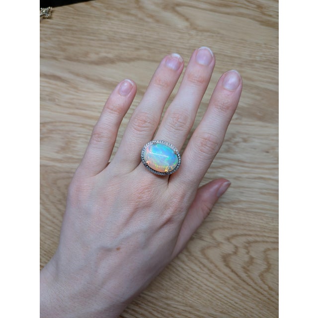 Make a bold impression with this gorgeous 9.43ct opal ring, showcasing a glowing 20x15mm opal framed by a halo of natural,...
