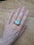 Make a bold impression with this gorgeous 9.43ct opal ring, showcasing a glowing 20x15mm opal framed by a halo of natural,...