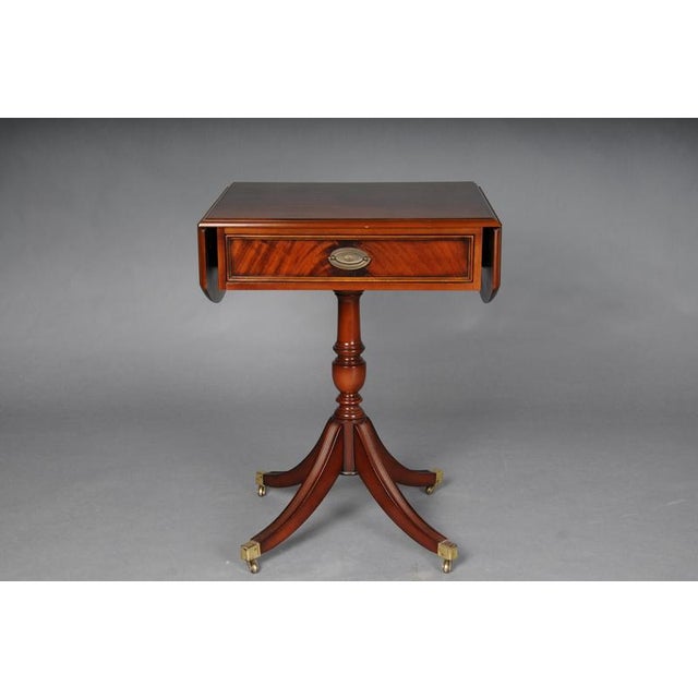 20th Century English Side Table, Mahogany This yew side table is a classic English design. It features a drop-leaf top,...