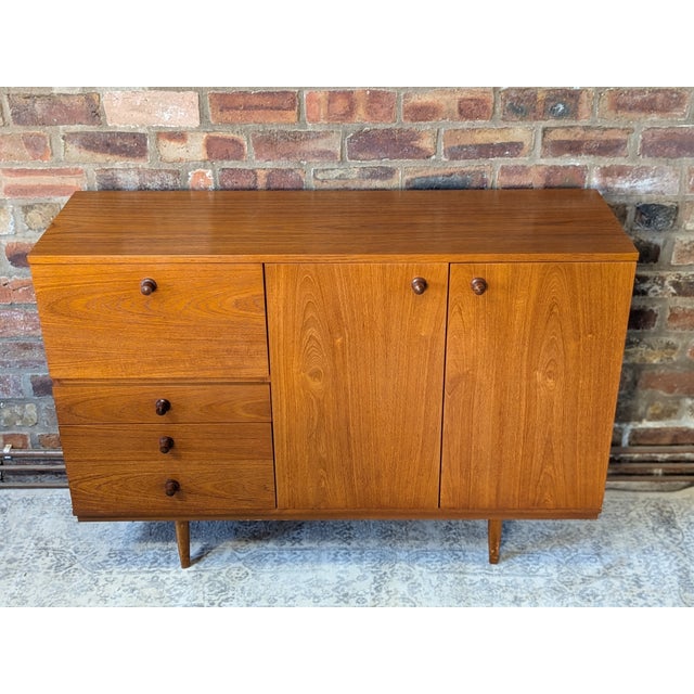 A classic mid-century sideboard by makers Avalon (makers mark in top drawer). Features a drop down cupboard with writing...